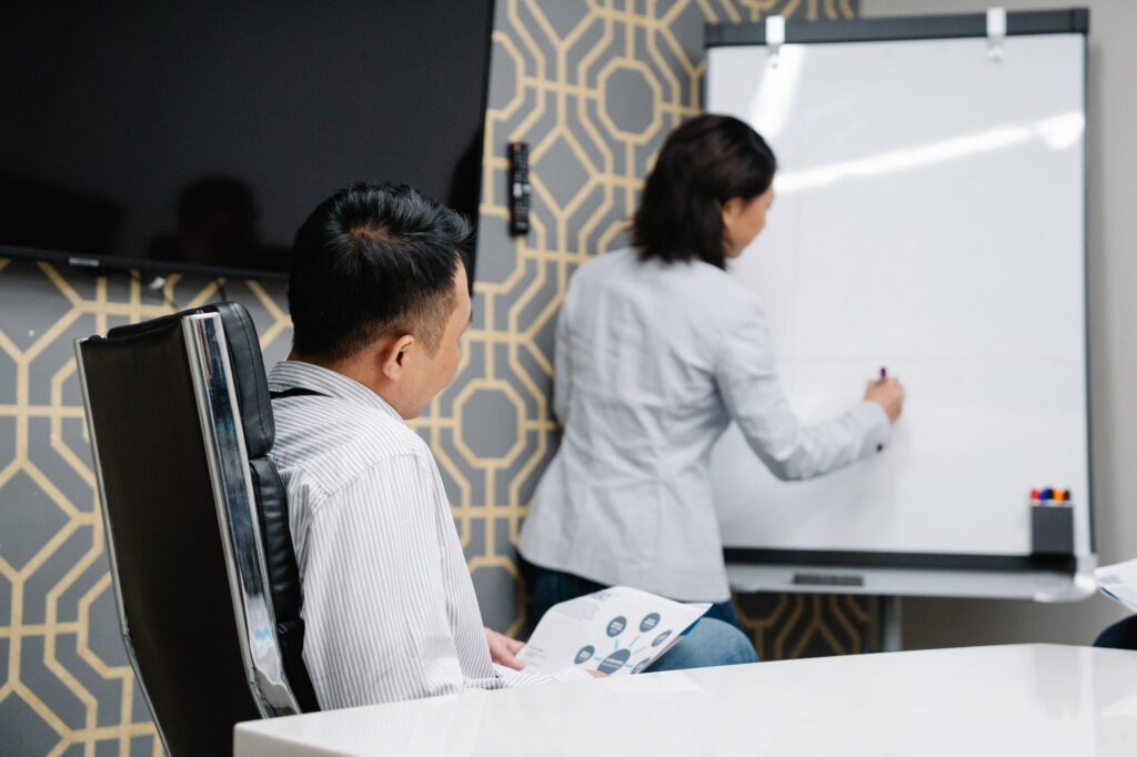 Colleagues brainstorming around a diagram on a whiteboard in a conference room