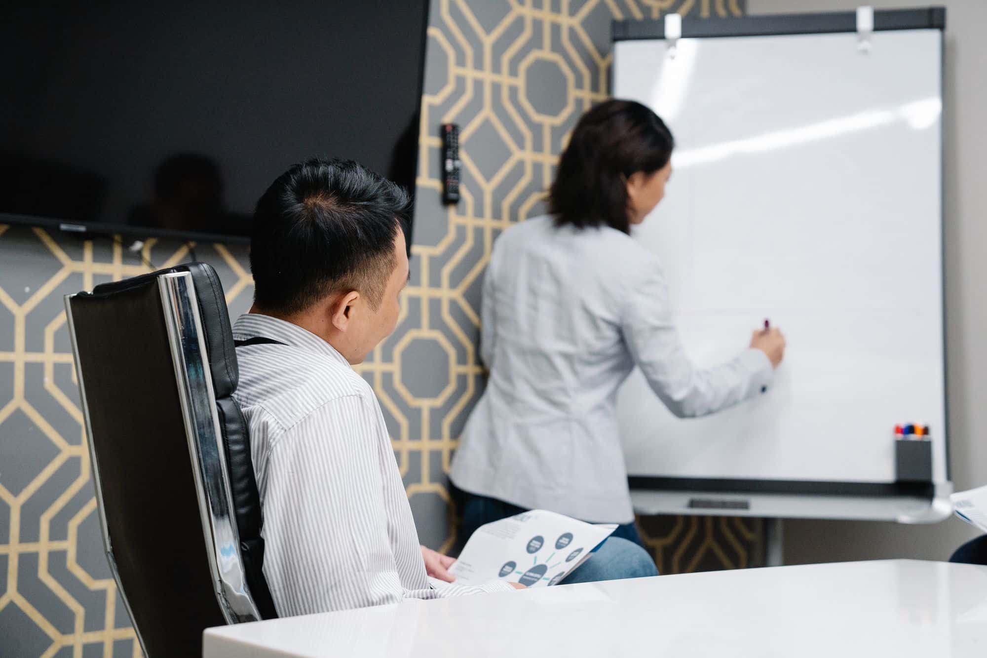 Colleagues brainstorming around a diagram on a whiteboard in a conference room