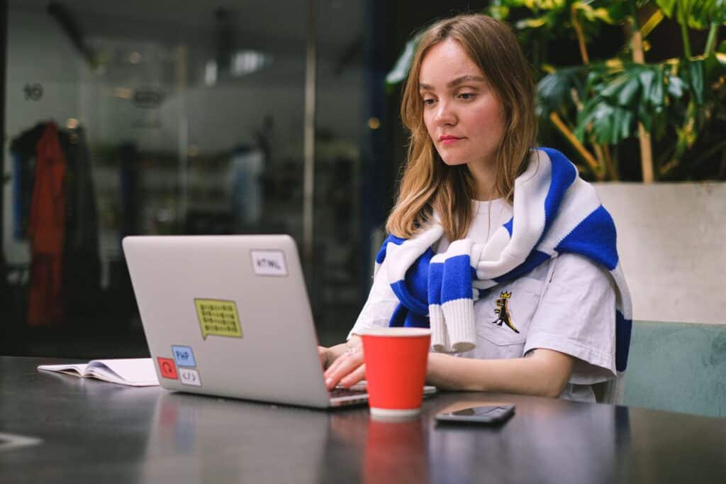 Frau arbeitet in einem modernen Café am Laptop, Symbolbild für ortsunabhängige Freelancer