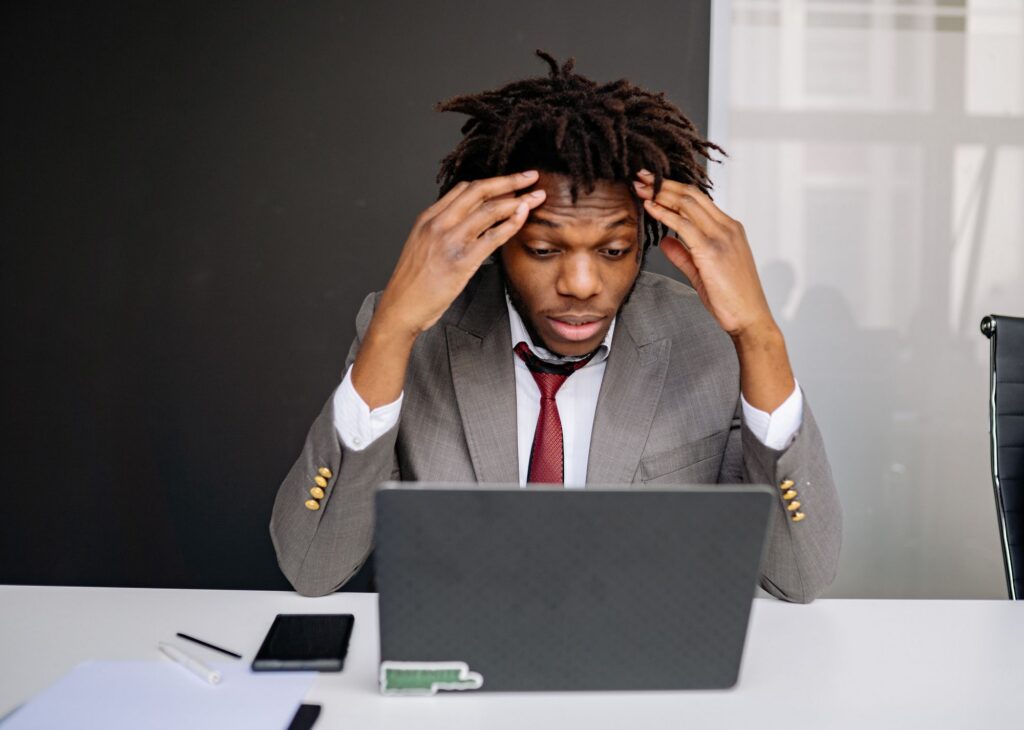 Frustrated seller with hands on head in front of a laptop