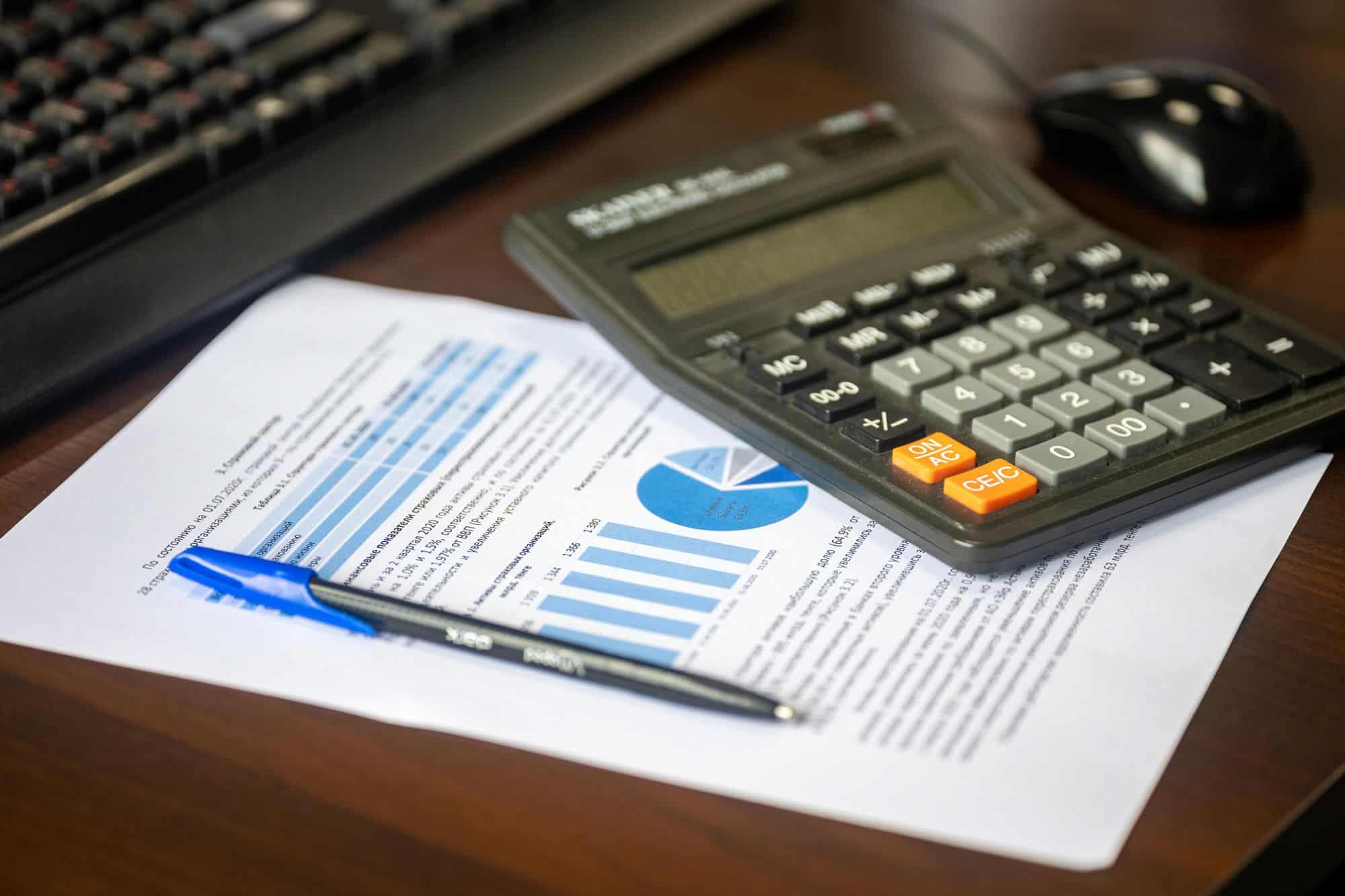 Masada hesap makinesi, grafikli basılı finansal rapor ve kalem